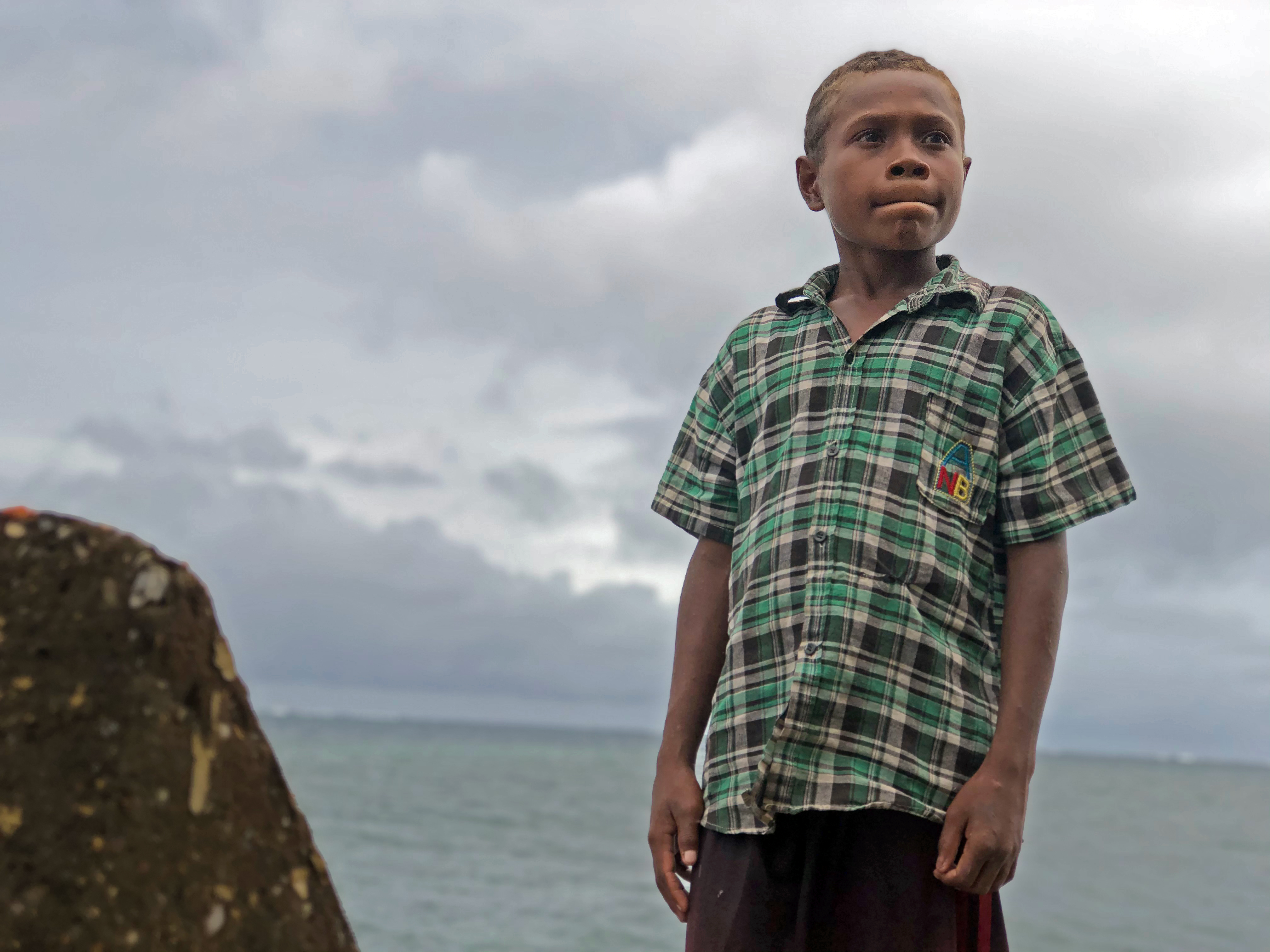 Timothy is standing on the island that he would have grown up on had it not been for climate change.